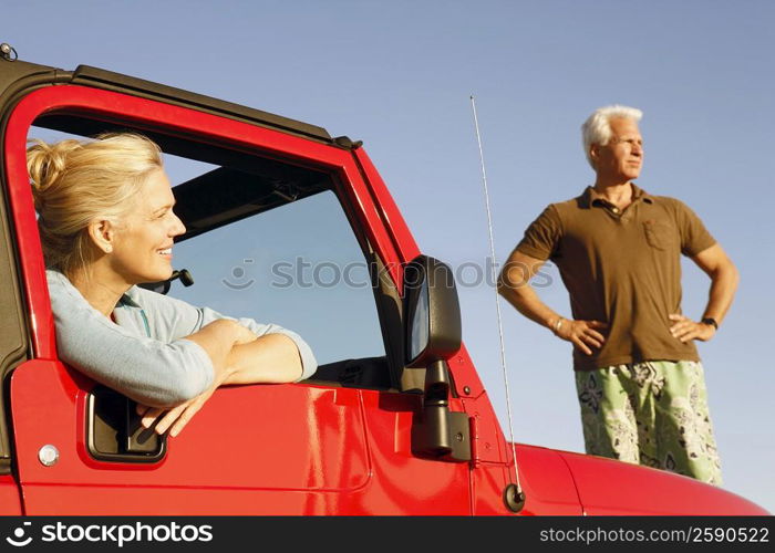 Close-up of a mature woman sitting in a sports utility vehicle with a mature man standing beside her