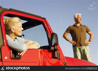 Close-up of a mature woman sitting in a sports utility vehicle with a mature man standing beside her