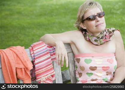 Close-up of a mature woman sitting on a bench in a lawn