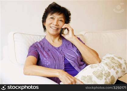 Close-up of a mature woman sitting on a couch and talking on a mobile phone