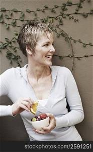 Close-up of a mature woman smiling and holding a bowl of fruit