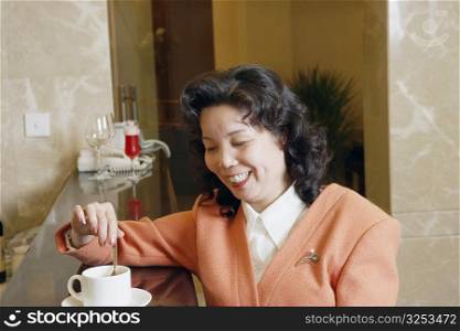 Close-up of a mature woman stirring a cup of coffee