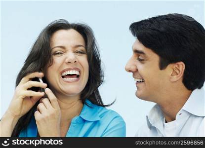 Close-up of a mature woman talking on a mobile phone with a mid adult man smiling beside her