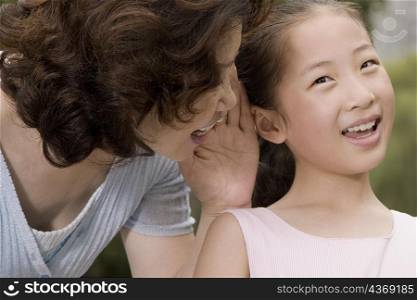 Close-up of a mature woman whispering into her granddaughter&acute;s ear