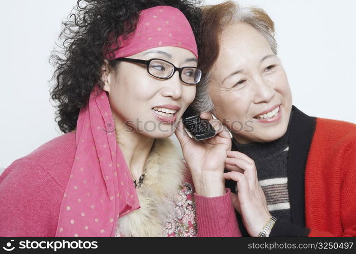 Close-up of a mature woman with her friends and using a mobile phone