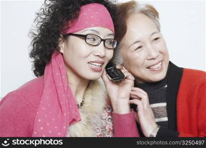 Close-up of a mature woman with her friends and using a mobile phone