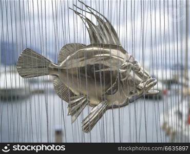 Close-up of a metal sculpture of fish behind bead curtain, Montenegro
