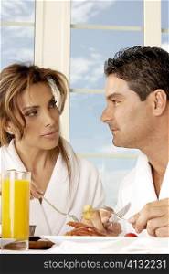 Close-up of a mid adult couple having breakfast and looking at each other