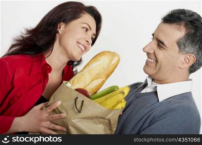 Close-up of a mid adult couple holding a shopping bag and smiling