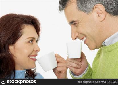 Close-up of a mid adult couple holding tea cups and smiling