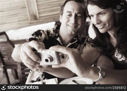 Close-up of a mid adult couple operating a digital camera in a restaurant