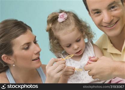 Close-up of a mid adult couple playing with their daughter