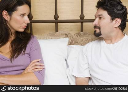 Close-up of a mid adult couple sitting on the bed and looking at each other