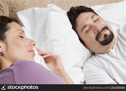 Close-up of a mid adult couple sleeping on the bed