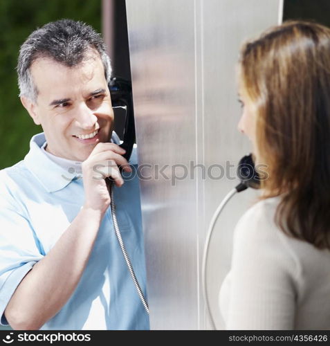 Close-up of a mid adult couple talking on a pay phone