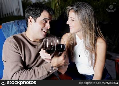 Close-up of a mid adult man and a mid adult woman holding glasses of red wine and smiling