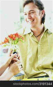Close-up of a mid adult man and a woman holding a flower vase and smiling in a restaurant