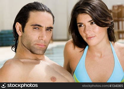 Close-up of a mid adult man and a young woman at the poolside
