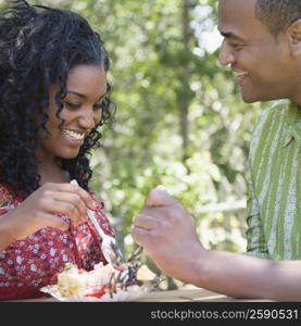 Close-up of a mid adult man and a young woman eating ice cream sundae