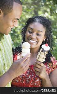 Close-up of a mid adult man and a young woman holding ice creams