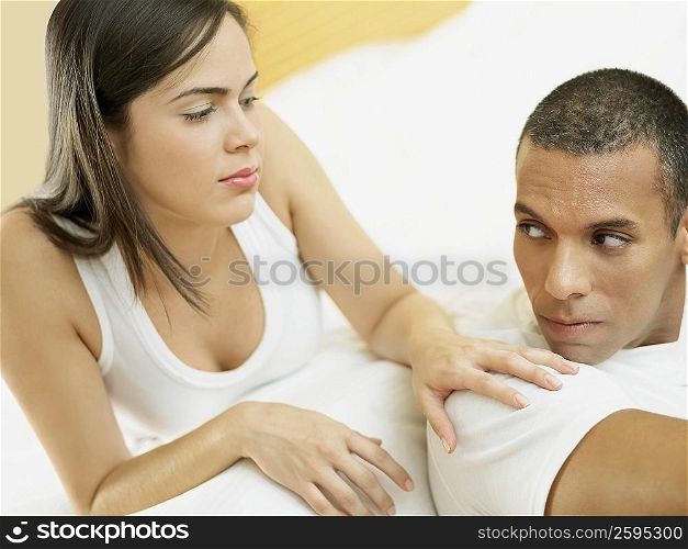 Close-up of a mid adult man and a young woman lying on the bed