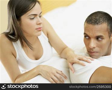 Close-up of a mid adult man and a young woman lying on the bed