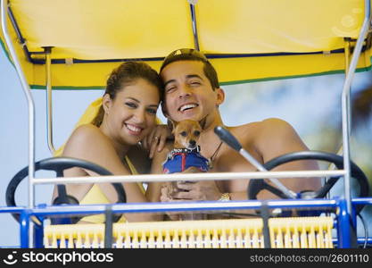 Close-up of a mid adult man and a young woman sitting on a buggy with a dog