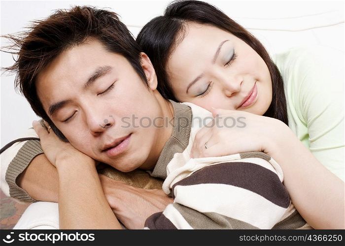 Close-up of a mid adult man and a young woman sleeping on a couch