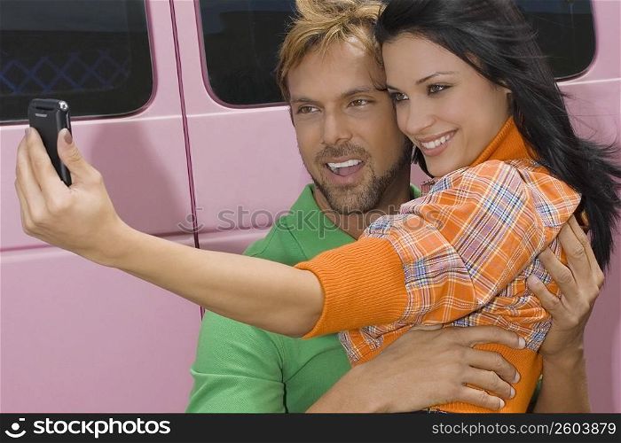 Close-up of a mid adult man and a young woman taking a photograph of themselves