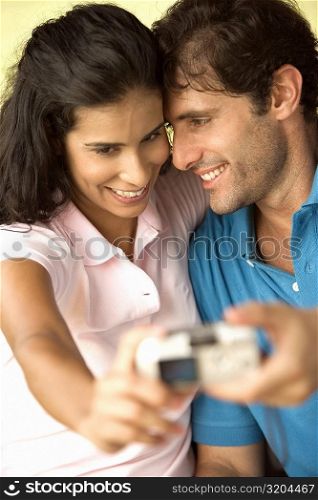 Close-up of a mid adult man and a young woman taking a photograph of themselves