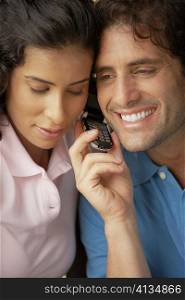 Close-up of a mid adult man and a young woman using a mobile phone