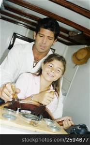 Close-up of a mid adult man and his daughter driving a motorboat