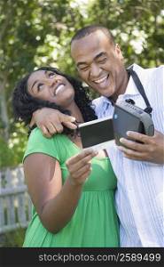 Close-up of a mid adult man arm around a young woman and holding an instant camera