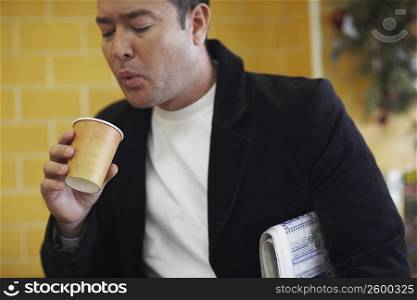 Close-up of a mid adult man blowing into a disposable cup