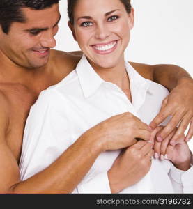 Close-up of a mid adult man buttoning a young woman&acute;s shirt