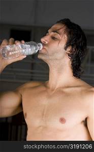 Close-up of a mid adult man drinking water from a bottle