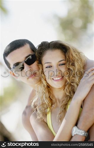 Close-up of a mid adult man embracing a young woman from behind