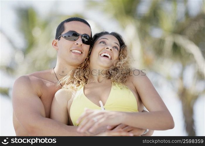 Close-up of a mid adult man embracing a young woman from behind
