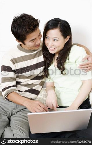 Close-up of a mid adult man embracing a young woman using a laptop