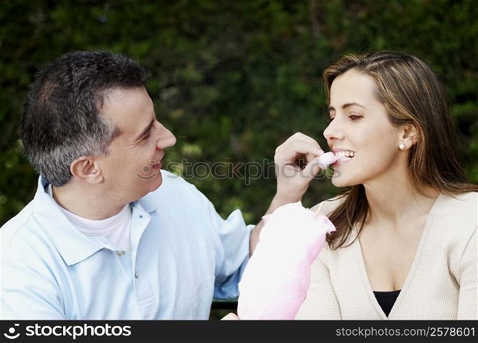 Close-up of a mid adult man feeding cotton candy to a mid adult woman
