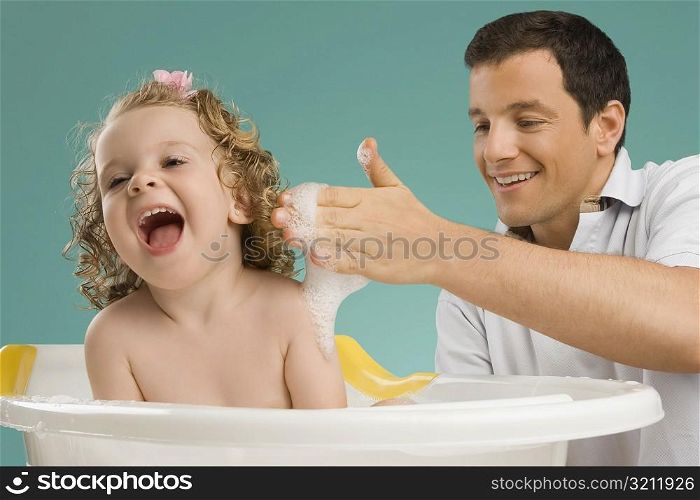 Close-up of a mid adult man giving bath to his daughter