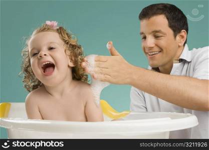 Close-up of a mid adult man giving bath to his daughter