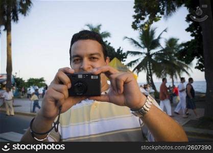 Close-up of a mid adult man holding a camera, Malecon, Santo Domingo, Dominican Republic