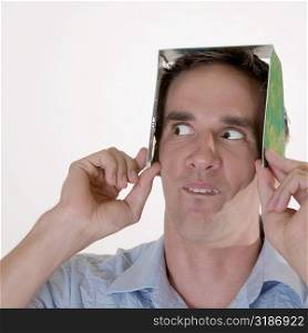 Close-up of a mid adult man holding a CD case on his head