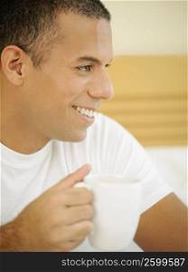 Close-up of a mid adult man holding a cup of tea and smiling