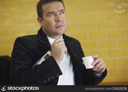 Close-up of a mid adult man holding a disposable cup and thinking