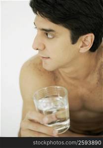 Close-up of a mid adult man holding a glass of water and looking sideways