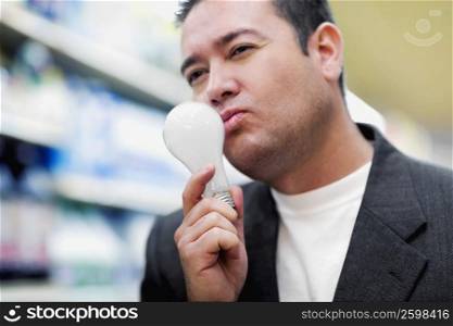 Close-up of a mid adult man holding a light bulb and thinking