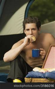 Close-up of a mid adult man holding a mug eating a piece of bread