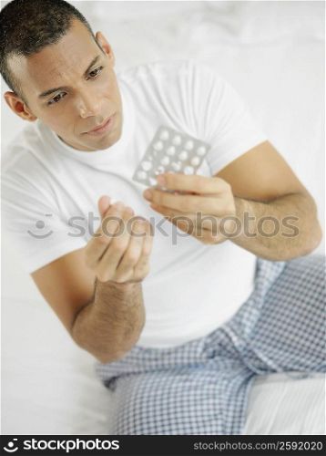 Close-up of a mid adult man holding a pill and a blister pack